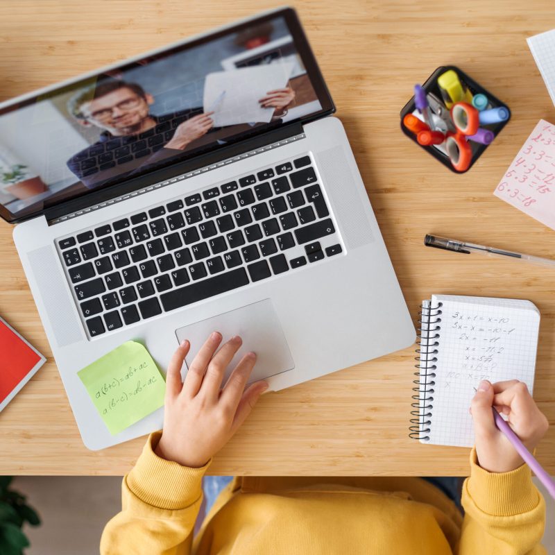 Top view of video conference with teacher on laptop at home. Close up of girls hands and video call with personal tutor on computer, online class, distance education, remote school, e-learning concept